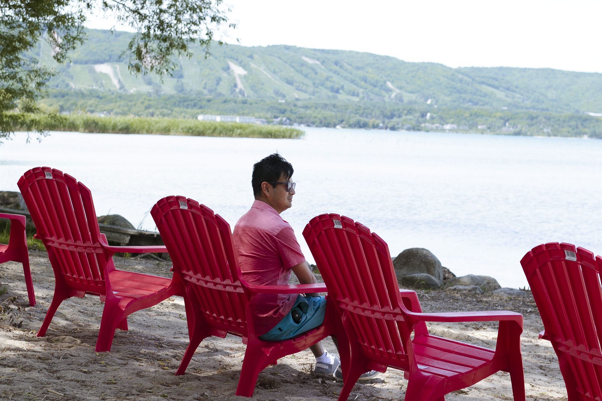 Red Muskoka chairs on the private sand beach looking across Georgian Bay to the Blue Mountain escarpment