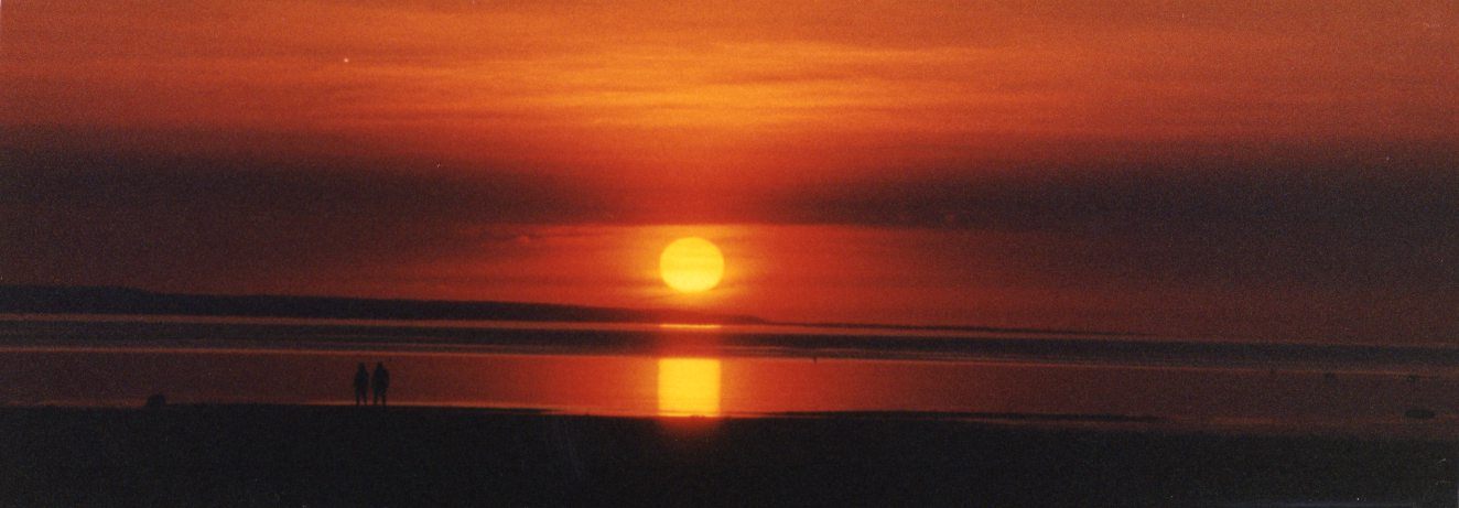 Two figures on the shoreline as the sun sets over Georgian Bay